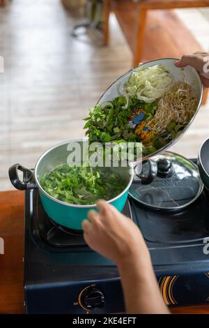 ingredienti biologici freschi in un piatto messo in una pentola in una lezione di cucina balinese su una stufa Foto Stock