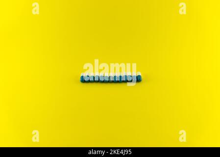 Pillole di colore blu e bianco in fila su una superficie blu. Forniture mediche. Foto Stock