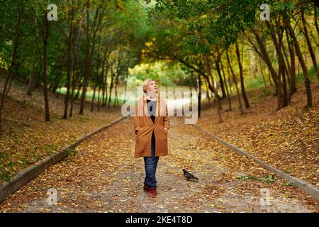 Felice donna pensionato caucasica all'aperto nel parco in stagione di caduta. Donna anziana sorridente che si gode la natura in autunno. Foto di alta qualità Foto Stock