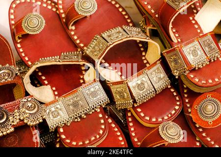 Coloratissime cappe fatte a mano (sandali) vendute in un mercato indiano, ciabatte in pelle fatte a mano, calzature tradizionali. Foto Stock