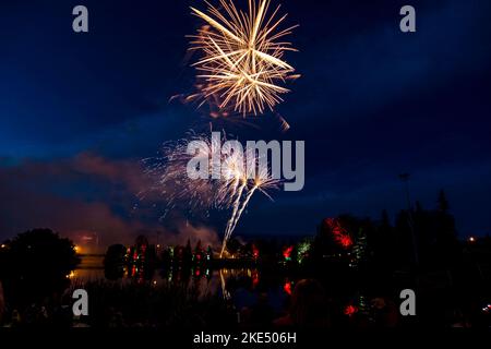 I fuochi d'artificio che illuminano il cielo notturno con la gente che guarda - il concetto di vacanza Foto Stock