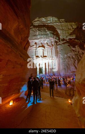 Turisti seduti di fronte al Tesoro a Petra Giordania illuminato da candele di notte Foto Stock