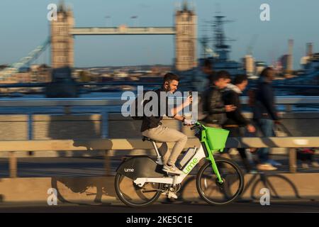 Un uomo che si trova a Londra durante l'ora di punta e che si trova a Londra durante il viaggio in bicicletta elettrica a noleggio. London Bridge, Londra, Regno Unito. 28 Ott 2022 Foto Stock