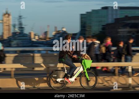 Un uomo che si trova a Londra durante l'ora di punta e che si trova a Londra durante il viaggio in bicicletta elettrica a noleggio. London Bridge, Londra, Regno Unito. 28 Ott 2022 Foto Stock