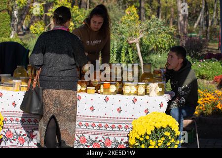 Chisinau, Moldavia - 15 ottobre 2022: Un sacco di diversi vasi di vetro di miele di marca polacca. Donna che acquista miele Foto Stock