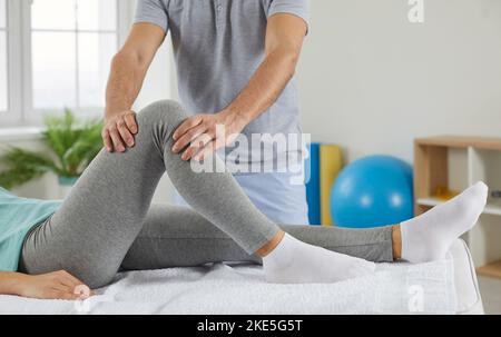 Paziente di sesso femminile e fisioterapista maschile durante il trattamento riabilitativo. Medico che sostiene il paziente con dolore alle gambe durante la riabilitazione Foto Stock