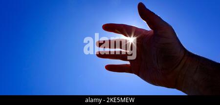 Mano che raggiunge verso il cielo in cerca di aiuto con sunstar Sunstar Sunshine guida all'ispirazione Foto Stock