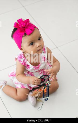 vista dall'alto di una bambina marrone seduta a terra che gioca con un dreamcatcher nelle sue mani. Foto Stock