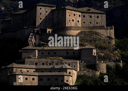 La luce del tardo pomeriggio si bagna sulle pareti e sui porti delle armi di Fort Bard, un baluardo italiano dei primi del 19th° secolo contro le invasioni francesi costruito nella ripida gola della Valle d'Aosta a Bard per controllare la stretta porta alpina verso il nord-ovest dell'Italia. La fortezza ospita oggi il Museo delle Alpi e molte altre attrazioni. Foto Stock