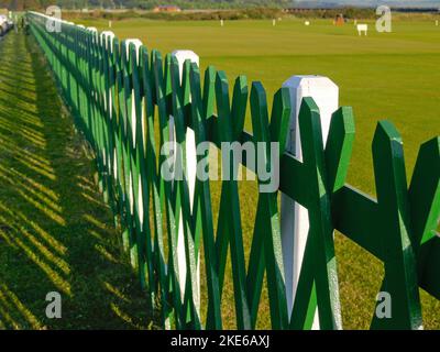 Recinzione di legno verde e bianco lungo il bordo del campo da golf in Scozia. Foto Stock