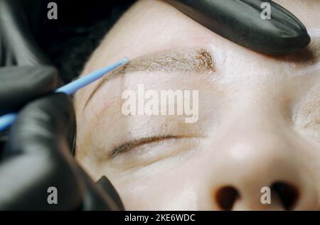 Primo piano. L'estetista pulisce le sopracciglia di una donna dopo la procedura di microblading. Foto Stock