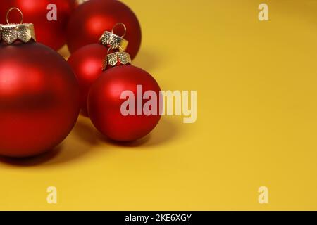 Palline ornamento rosso di Natale su sfondo giallo. Disposizione piatta, vista dall'alto, spazio di copia Foto Stock