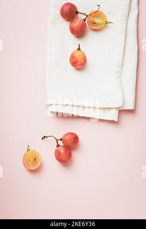 Uva rossa su sfondo rosa, vita morta minima, vista dall'alto Foto Stock