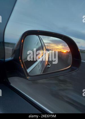 Tramonto nello specchio retrovisore di un'auto. Foto di alta qualità Foto Stock