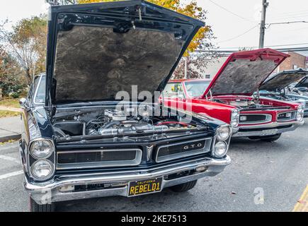 Un blu e un rosso 1960's Pontiac GTO's con cofani in su che espongono i motori ed i restauri all'ultima esposizione dell'automobile della stagione sulla strada principale Foto Stock