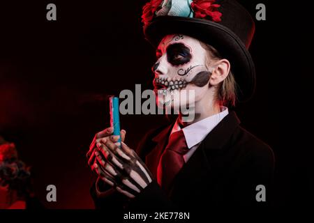 Donna vestita come santa muerte soffiare candela in studio, mettendo fuori fuoco fiamma e indossando la dea della morte compongono. Festeggiamo il giorno della tradizionale festa messicana morta di Halloween. Foto Stock
