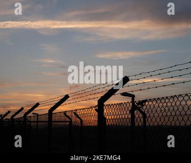 Silhouette di filo spinato per concertina su un recinto di prigione Foto Stock