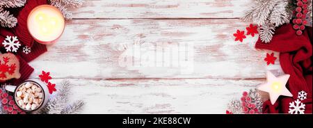 Accogliente Natale o inverno doppio bordo con maglione rosso, candele, cioccolata calda, rami gelido e arredamento. Vista dall'alto su un banner rustico in legno bianco b Foto Stock