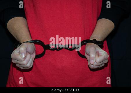 Foto di un paio di mani da donna con anelli di ferro davanti a una camicia rossa. Foto Stock