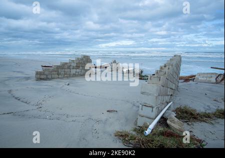 Resti di un muro di mare distrutto dall'uragano Nicole affondano nella sabbia. Foto Stock