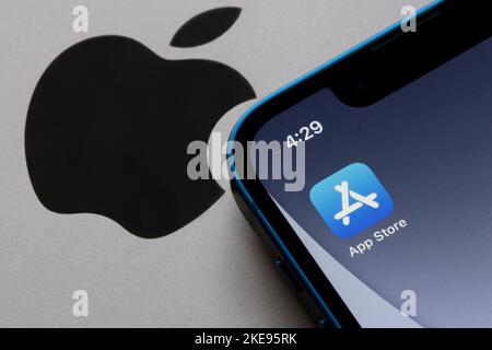 L'icona dell'App Store è visibile su un iPhone in cima a un MacBook con il logo Apple. Consente agli utenti di sfogliare e scaricare le app approvate sviluppate all'interno del sito ... di Apple Foto Stock