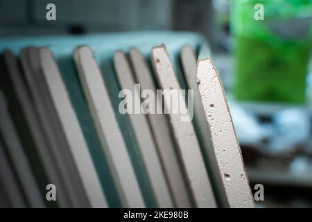 Molti fogli di cartongesso resistenti all'umidità in primo piano in un cantiere. Materiale di rivestimento universale. Materiali da costruzione piegati dopo la consegna. Te Foto Stock