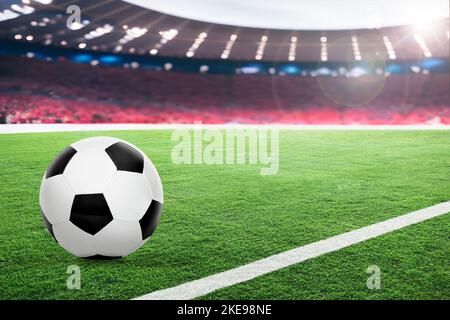 Football in uno stadio all'aperto fittizio e luminoso con spettatori e luce solare. Fuoco sulla sfera di calcio di primo piano con profondità di campo bassa sul retro Foto Stock
