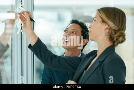 Fare buon uso delle sue abilità. Colleghi che usano appunti appiccicosi contro la parete durante una sessione di brainstorming. Foto Stock