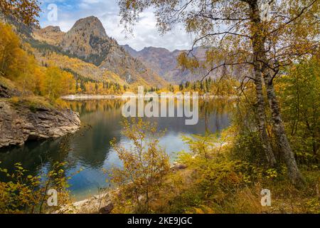 Vista del Lago di Antrona nei colori autunnali dal sentiero intorno al lago, Valle Antrona, Piemonte, Italia. Foto Stock