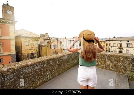 Ragazza viaggiatore godendo il paesaggio urbano di Orvieto da una terrazza di palazzo storico, Orvieto, Umbria, Italia Foto Stock
