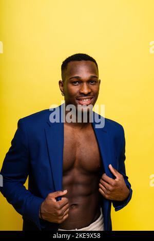 Ragazzo in tuta blu su sfondo giallo. Bell'uomo atletico in giacca sorridente Foto Stock