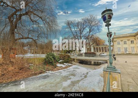 La neve dispersa sotto il cielo nuvoloso blu nel Parco Lazienki Krolewskie a Varsavia, Polonia Foto Stock