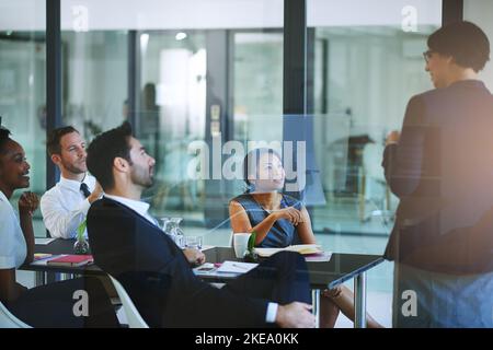 Ha la loro attenzione, una donna d'affari che fa una presentazione nella sala del consiglio. Foto Stock