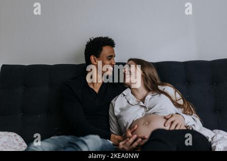 Donna incinta con partner a letto Foto Stock