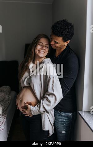 Donna incinta con partner in piedi insieme Foto Stock