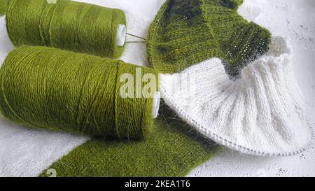 Maglione fatto a mano. Tessuto lavorato a maglia in filo di visone. Motivo colore bianco e oliva. Spazio copia. Foto Stock