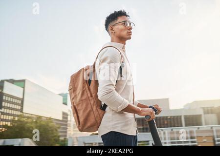 Viaggia, calci elettrici e un uomo in città, rilassati e guida fino al campus, senza emissioni di carbonio e rispettoso dell'ambiente con mockup. Studente. Scooter e nero Foto Stock