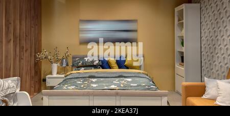 Fotografia interna, ampia camera da letto con letto grande. interno della camera da letto con lenzuola di colore giallo e immagine sulla parete dolce stile casa, legno Foto Stock