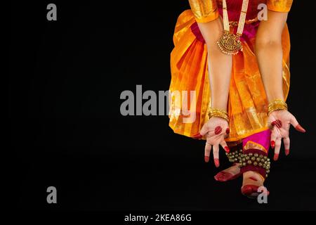 La ballerina classica indiana femminile che esegue la danza Bharatanatyam si pone su sfondo scuro con spazio di copia. Foto Stock
