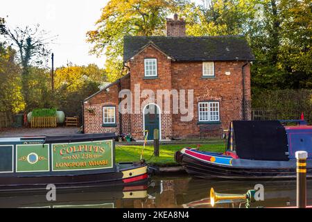 Vecchie barche a remi di canale funzionanti da Longport Wharf ormeggiate sul canale Shropshire Union all'esterno di un cottage canale a Nantwich Cheshire Foto Stock