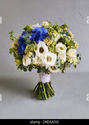 Bouquet nuziale rotondo su fondo grigio cemento. Il bouquet di nozze è composto da freesia, Matthiola, lisianthus, dianthus, Hydrangea blu e. Foto Stock