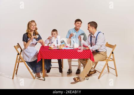 Famiglia allegra, moglie bellissima, due figli e marito seduti al tavolo e a colazione Foto Stock