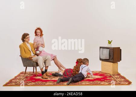 Ritratto di famiglia giovane guardando la TV isolato su sfondo grigio Foto Stock