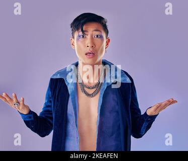 Shock, sorpresa e gay con trucco in studio isolato su uno sfondo viola. Cosmetici, cyberpunk e lgbtq, queer e punk modello maschile da Foto Stock