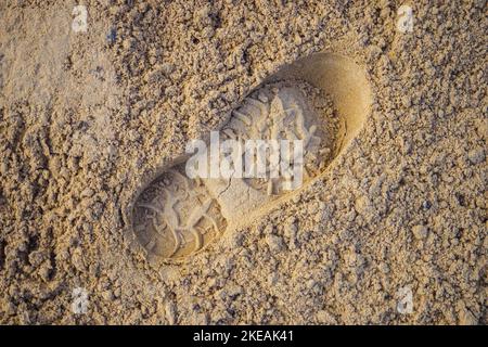 Ingombro maschio singolo. Footprint da scarpa o vanga in sabbia. Sfondo.. Foto Stock