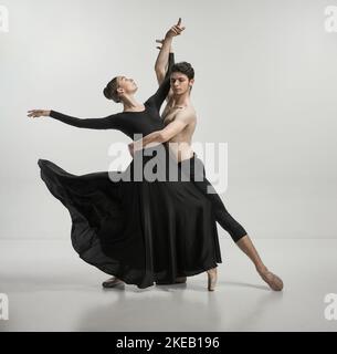 Giovane uomo e donna, ballerini ballerini che si esibiscono isolati su sfondo grigio studio tenerezza e passione Foto Stock