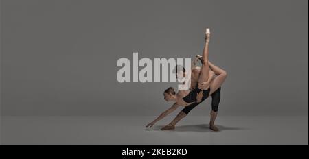 Giovane uomo e donna, ballerini balletto che si esibiscono sul palco isolato su sfondo grigio scuro studio. Volantino Foto Stock