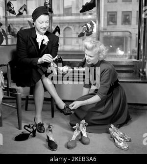 Negozio di scarpe negli anni '1940s. Una donna nella scarpa su Hamngatan Stoccolma 1948. Sembra cercare qualcosa di speciale nelle nuove scarpe che sta cercando, e hanno diversi paia di scarpe da provare. Svezia 1948. Rif. Conard 950 Foto Stock