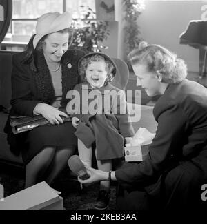 Negozio di scarpe negli anni '1940s. Una bambina con la madre in un negozio di scarpe di Stoccolma. Sembra felice e sorride quando l'addetto alle vendite indossa le nuove scarpe in piedi. Svezia 1948. Rif. Conard 950 Foto Stock