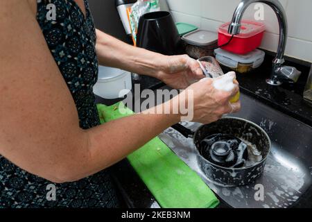 Giovane donna lavando pentola e utensili in cucina. Igiene in cucina. Salvador, Bahia, Brasile Foto Stock